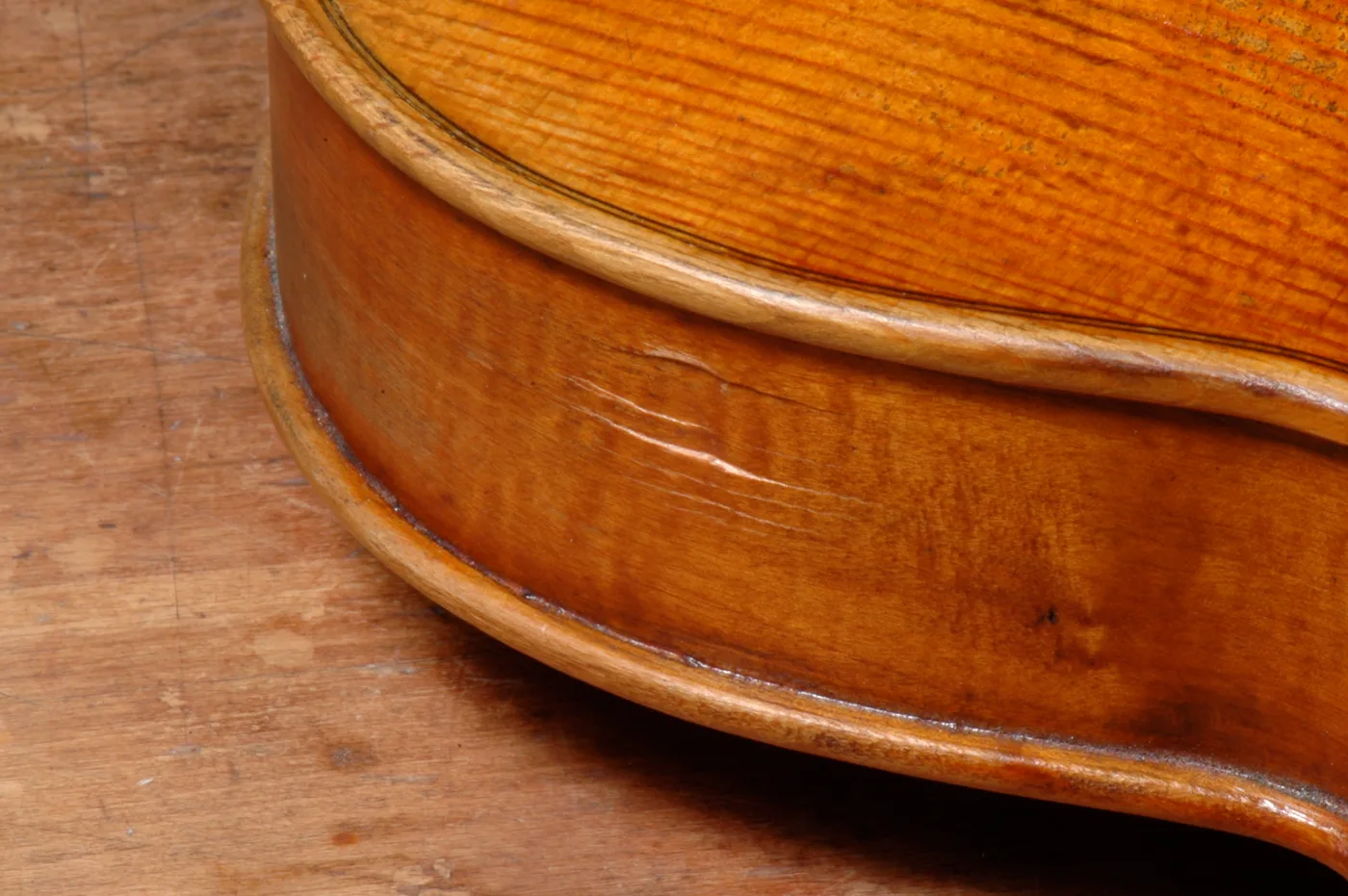 The rib and edge of a violin, varnish catching the light.